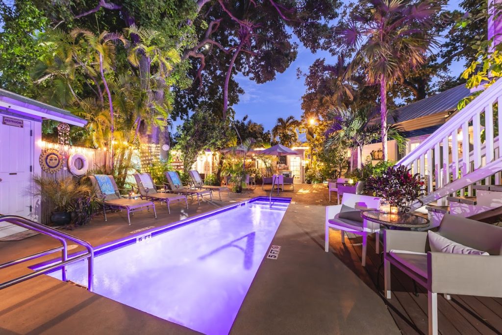 Tropical poolside lounge area with lush greenery at night