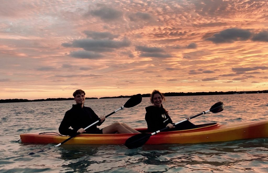 Two people kayaking on a lake during a beautiful sunset