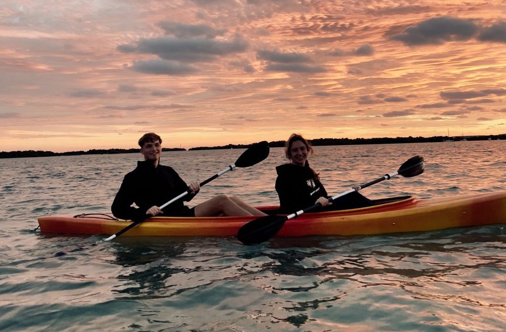 Two people kayaking on a serene lake during a stunning sunset