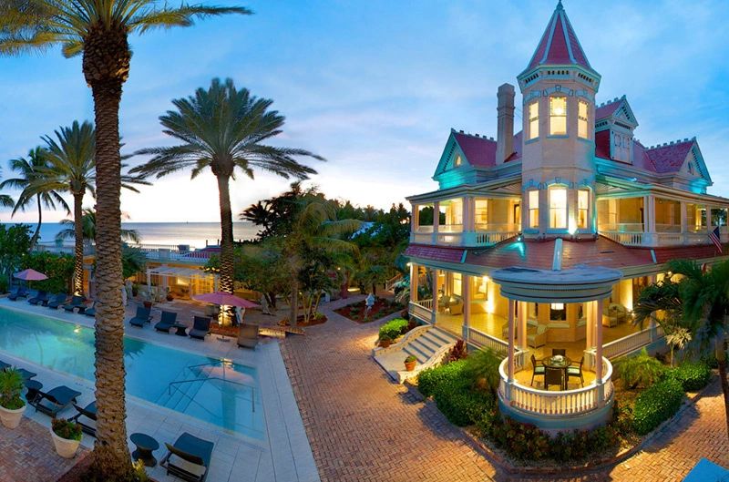 Victorian style mansion with pool and ocean view during sunset.