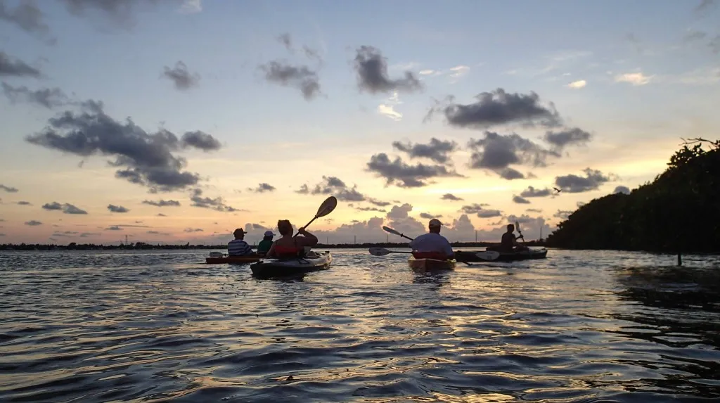 People kayaking on a serene lake during a stunning sunset
