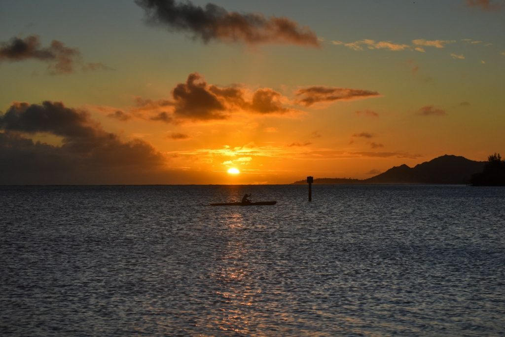 Kayaker enjoying a peaceful ocean sunset with mountains nearby