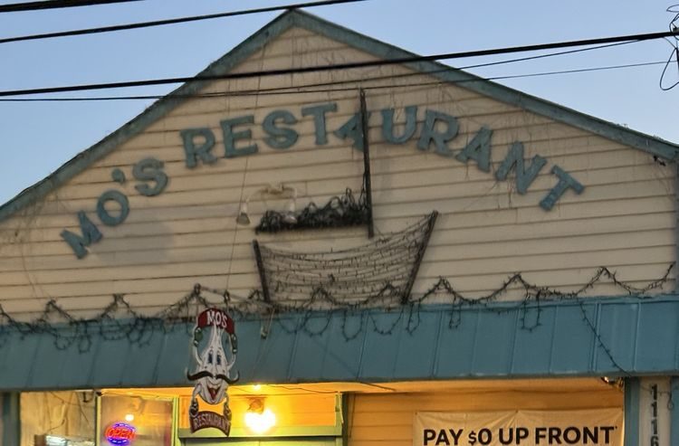 Exterior of Mo's Restaurant at dusk with illuminated signs