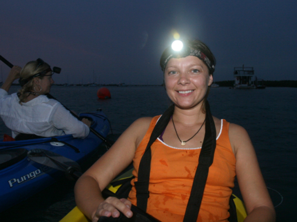 Woman kayaking at night with headlamp on calm water
