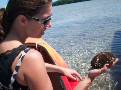 woman holding a sea creature while seated in kayak